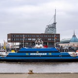 Ein Fährschiff fährt vor Gebäuden entlang.