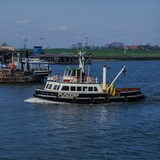 Ein kleines Schiff fährt einen Fluss entlang.