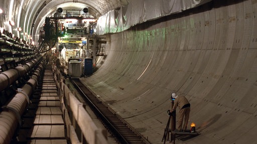 Ein Vermessungstechniker arbeitet in der bisher zur Hälfte verlegten Röhre des Wesertunnels 