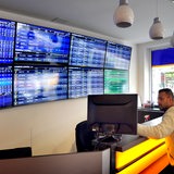 Innenaufnahme eines Wettbüros: An der Wand sind Flachbildschirme, sogenannte Livescreens, auf denen die Ergebnisse von Sportereignissen live gezeigt werden. 