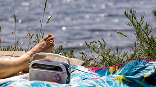 Ein Radio steht auf einer Decke am See