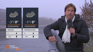 Links die Wettertafeln, rechts Wettermoderator Andree Pfitzner. Im Hintergrund fließt die Weser in diesiger Nebeligkeit.
