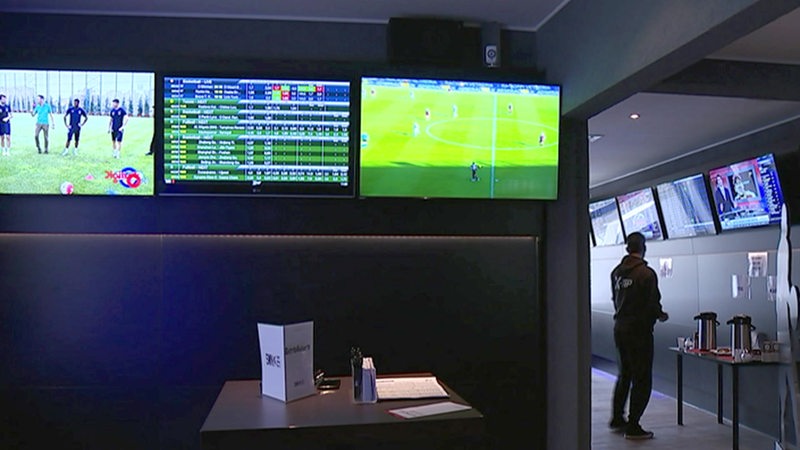Monitore mit Sportübertragungen in einem Wettbüro.