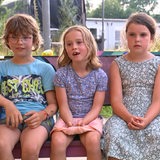 Mehrere Kinder sitzen auf einer Bank.