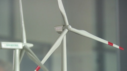 Zwei Modelle von Windkrafträdern vor verschwommenem Hintergrund. 