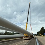 Die Rotoren einer Windkraftanlage liegen auf einem Selbstfahrer für den Transport bereit.