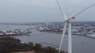 Ein Windrad im Fordergrund, dahinter die Weser und Bremerhafen von oben zu sehen.