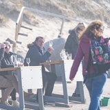 Menschen sitzen in dicken Jacken in einer Strandbar an der Nordsee.