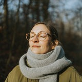 Eine Frau hält im Winter ihr Gesicht in die Sonne (Symbolbild)