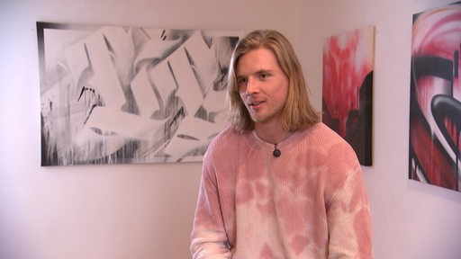Zu sehen ist der Eishockeyspieler Moritz Wirth während eines Interviews in einer Kunstgalerie.