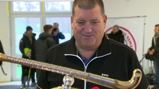 Sportdirektor Martin Schultze sieht auf den Wm-Pokal.