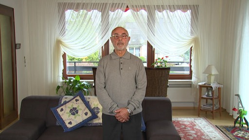 Der als Gastarbeiter nach Deutschland gekommene Rentner Abdullah Süleyman Akcur steht in seinem Wohnzimmer.