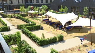 Auf dem Innenhof eines Wohngebietes in der Überseestadt stehen Zelte, Bänke und Tische für die Eröffnungsfeier.