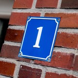 Ein Schild mit der Hausnummer "1" an einer Wand aus Ziegelsteinen.