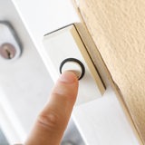 Ein Finger drückt die Klingel an einer Wohnungstür