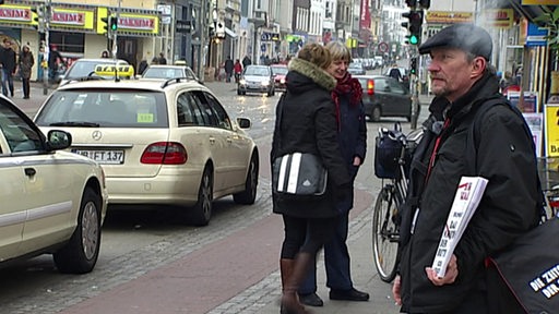 Ein Obdachloser mit Ausgaben der Zeitschrift der Straße steht an einer Kreuzung in Bremen.