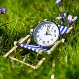 Weiße Uhr im Liegestuhl im Gras.