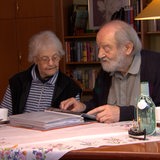 Gretchen und Heinrich Benjes sitzen am Tisch und schauen sich Fotos an.