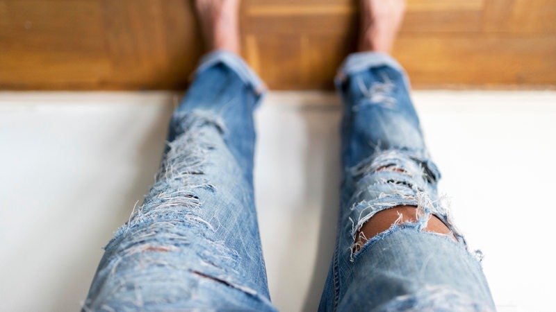 Eine Person trägt eine Hose mit zerrissenen Jeans
