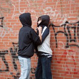 Ein Teenager drückt einen kleineren Jungen gewaltsam gegen eine Wand.