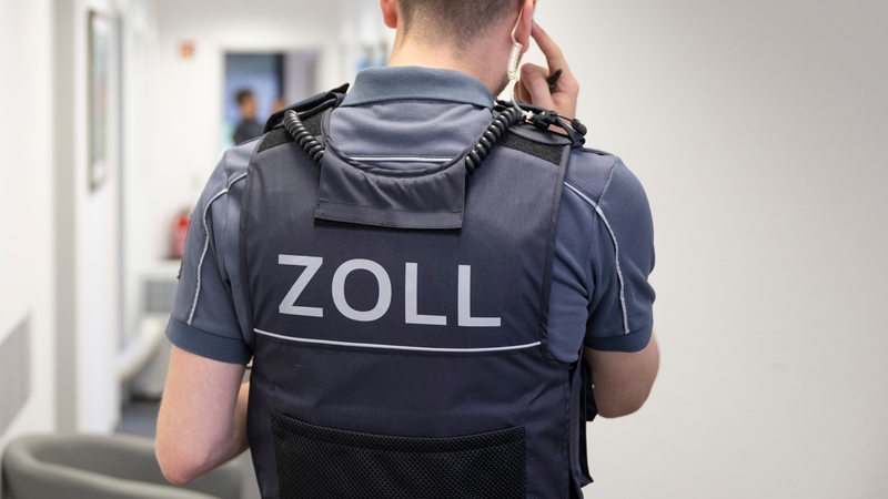 Ein Zollbeamter steht im Flur eines Bürogebäudes.