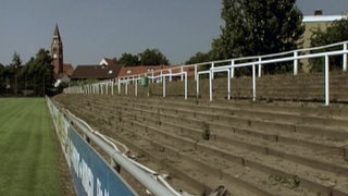Eine leere Tribüne, vor einem Fußballfeld.