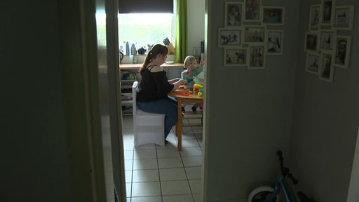 Ein kleines Kind sitzt mit seiner Mutter am Küchentisch