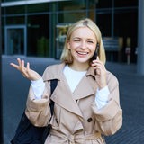 Eine junge Frau telefoniert und lacht dabei.