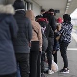 Flüchtlinge aus einem Zug aus Österreich werden von Grenzwächtern zur Kontrolle gebracht.