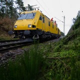 Auf einem Reparaturzug stehen Arbeiter, die eine Oberleitung reparieren
