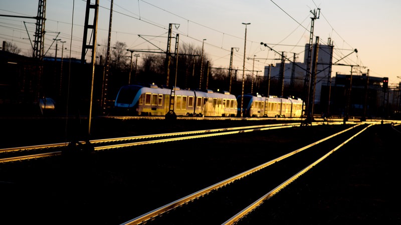 Ein Zug steht während des Sonnenaufgangs auf einem Gleis.