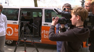 Eine Schülerin hält am Zukunftstag eine Kamera vor dem buten un binnen Fahrzeug. 