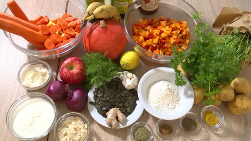 Viele verschiedene Zutaten zum Kochen liegen auf einem Tisch.