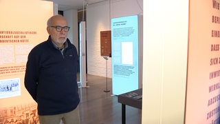 Ein Mann sieht sich eine Ausstellungstafel an.