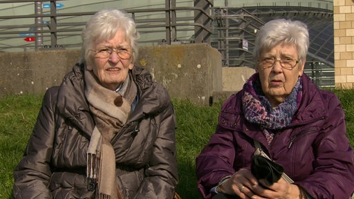 Zwei Jugendfreundinnen aus Bremerhaven haben sich nach 70 Jahren wiedergefunden. Sie sitzen gemeinsam auf einer Wiese am Meer.