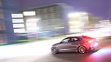 Ein sportliches Auto fährt vor verwischtem Hintergrund auf einer Straße.