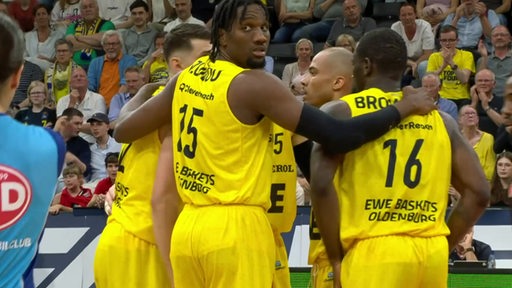 Es stehen mehrere Oldenburger Basketballspieler in einem Kreis und tauschen sich aus.