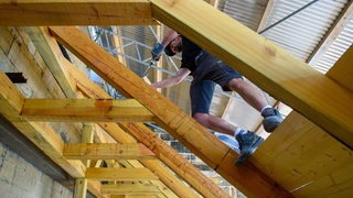 Ein Mann arbeitet mit einer Bohrmaschine an einer Dachkonstruktion.