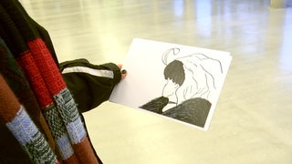 Eine Person hält eine Kippfigur Zeichnung in der Hand. 