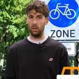 Ein Mann neben einem Schild "Fahrradzone" spricht in die Kamera.