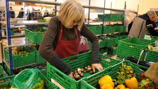 Eine Frau sortiert ehrenamtlich Gemüse und Obst bei der Tafel