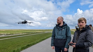 Die Geografen Steffen Dietenberger und Marlin Müller vom Institut für Datenwissenschaften des Deutschen Zentrum für Luft- und Raumfahrt steuern eine Drohne auf einem Deich.