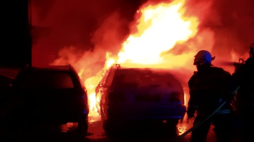Drei brennende Autos vor einer Gewerbehalle