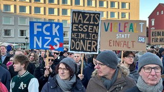 Demonstrierende in Bremerhaven halten Schilder hoch