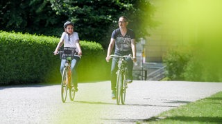 Ein Mann und eine Frau fahren mit ihren Rädern durch einen Park.