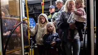 Eine Mutter mit ihren Kindern, evakuiert aus Mariupol, kommt mit dem Bus in Saporischschja an