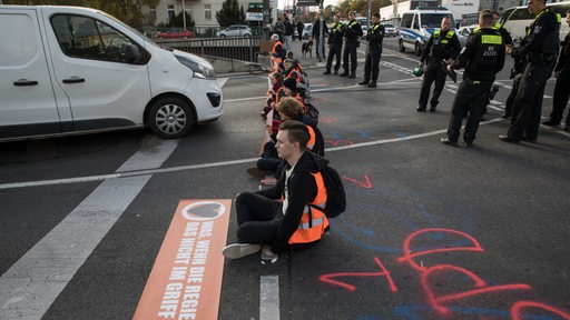 Klimaaktivisten blockieren in Berlin eine Straße.