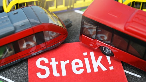 Minitaturen von Bus und Bahn mit einem Streik-Schild