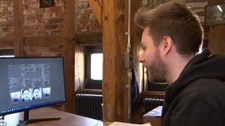 Ein Fotograf guckt sich im Computer ein Video manipuliert mit Künstlicher Intelligenz an. 