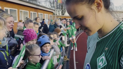 Eine Werder-Spielerin gibt Kindern Autogramme 